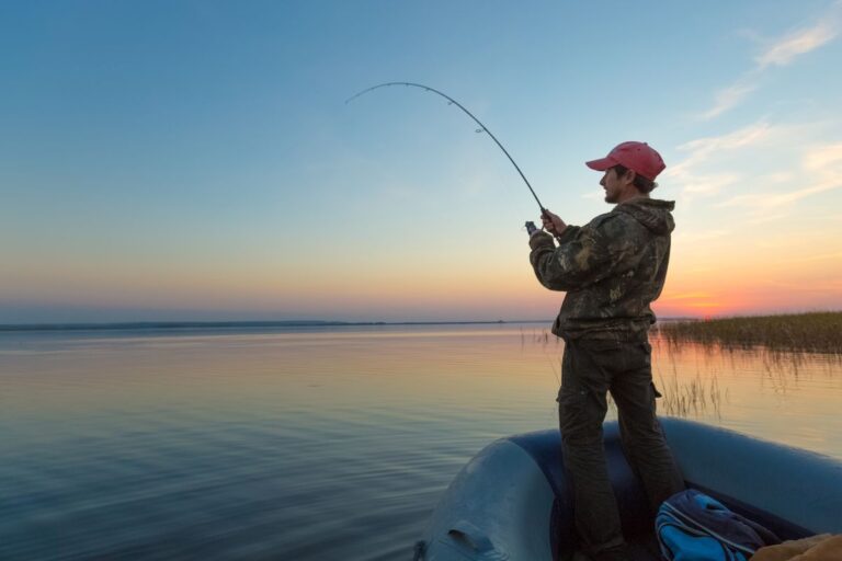 A man on a boat fishing on sunset.