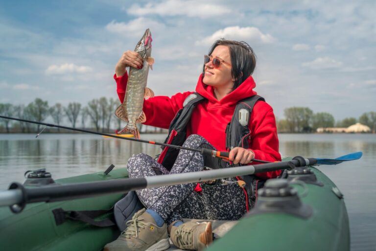 A woman holding her catch on a kayak.