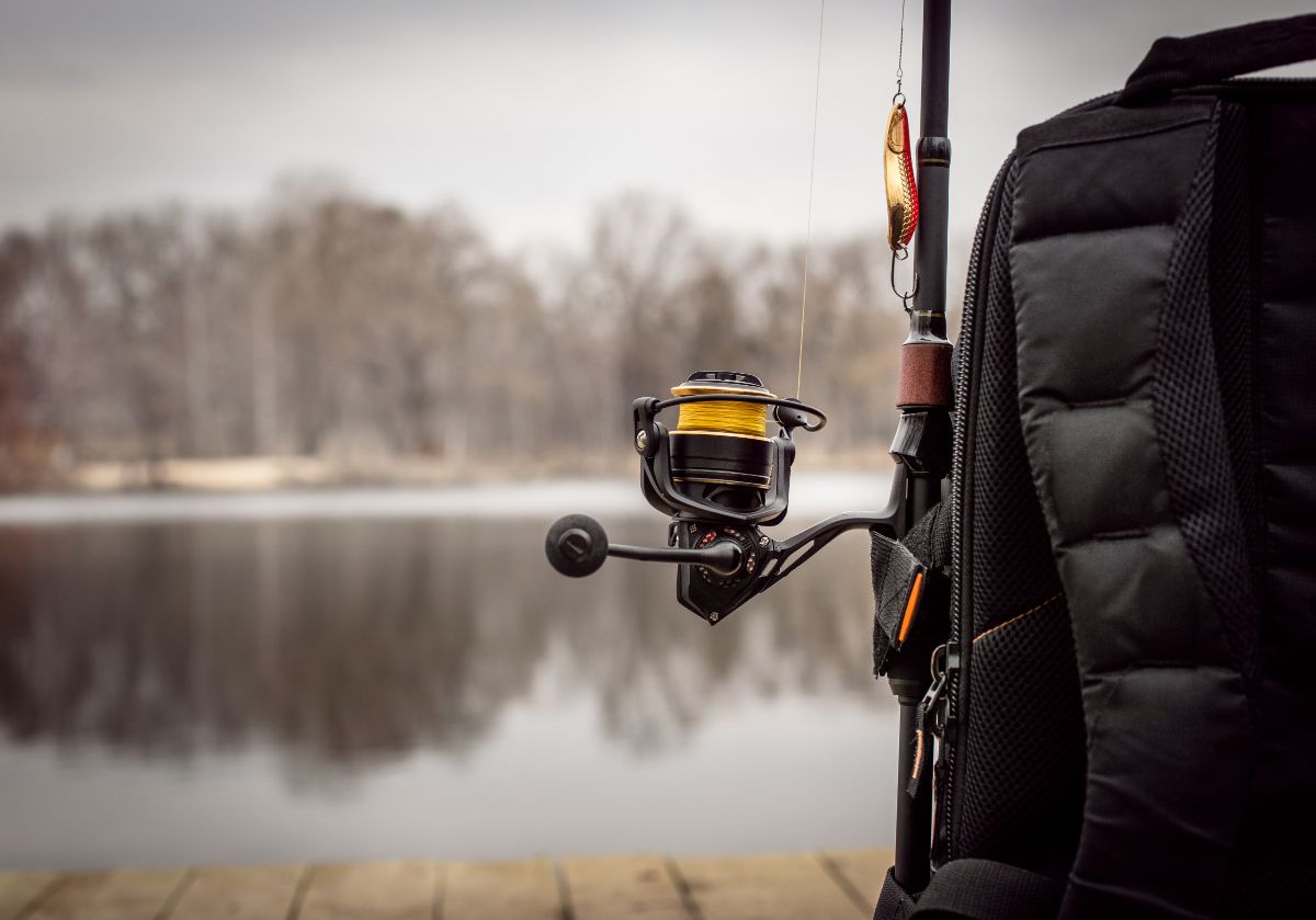 A fishing rod on a backpack at the dock.